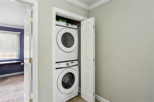 laundry area featuring baseboards, ornamental molding, laundry area, carpet flooring, and stacked washer / drying machine