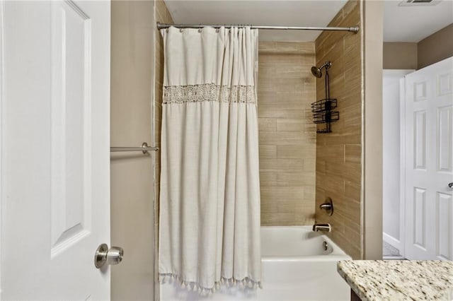 bathroom featuring visible vents, shower / bath combo with shower curtain, and vanity