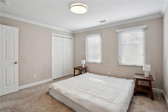 carpeted bedroom featuring visible vents, baseboards, a closet, and ornamental molding