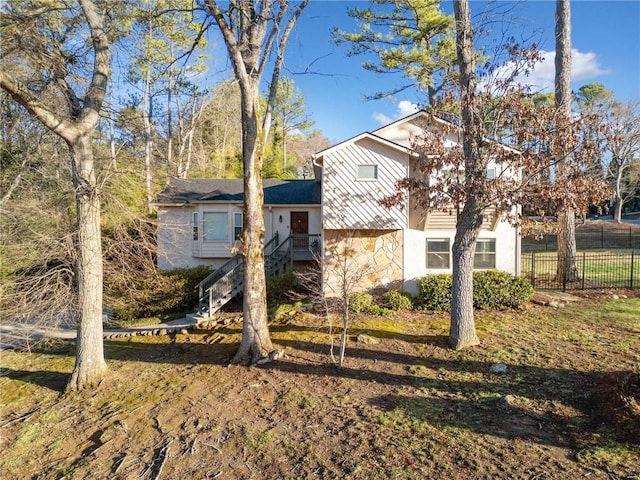 view of front of house featuring stairs, fence, and stone siding