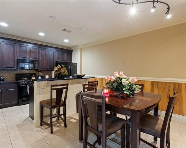 interior space with a center island, crown molding, a breakfast bar area, and black appliances