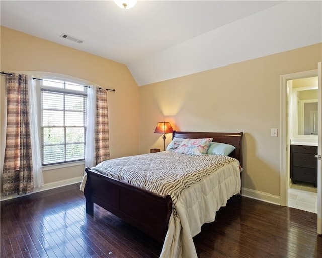 bedroom with dark hardwood / wood-style flooring, ensuite bathroom, and lofted ceiling