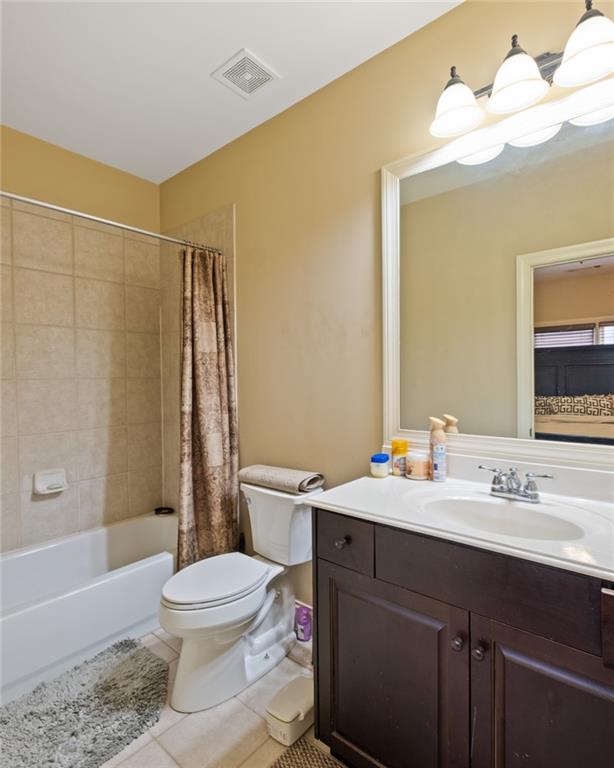 full bathroom featuring vanity, shower / bath combo with shower curtain, tile patterned flooring, a chandelier, and toilet