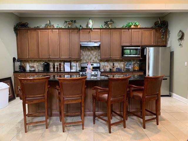 1301 Haven Cir, Douglasville, GA 30135 - kitchen featuring appliances with stainless steel finishes, under cabinet range hood, dark countertops, decorative backsplash, and ornamental molding