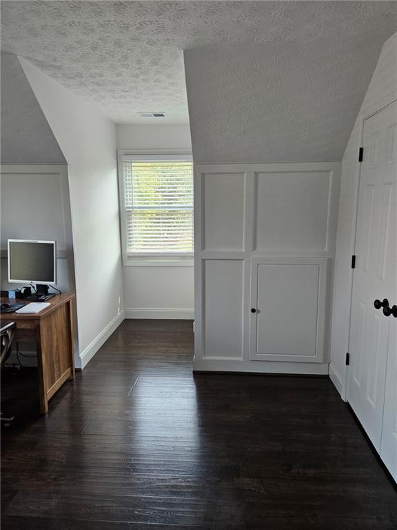2467 Sky Valley Dr, Dacula, GA 30019 - unfurnished bedroom featuring a textured ceiling, dark wood-style flooring, and an office area