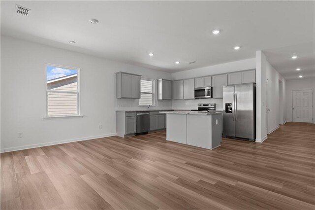 3011 Orwell Dr, Gainesville, GA 30507 - kitchen with light wood-style flooring, a kitchen island, gray cabinets, appliances with stainless steel finishes, and baseboards