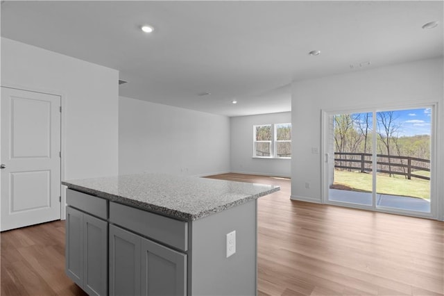 3011 Orwell Dr, Gainesville, GA 30507 - kitchen with recessed lighting, gray cabinets, light wood-style flooring, a kitchen island, and light stone counters