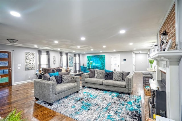 living area featuring a fireplace, baseboards, wood finished floors, and recessed lighting