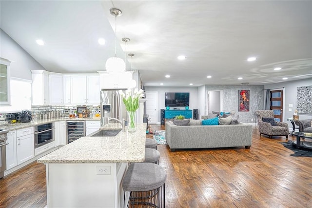 kitchen with a kitchen breakfast bar, wine cooler, a sink, appliances with stainless steel finishes, and white cabinetry