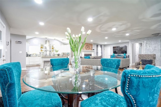 dining space with recessed lighting, wood finished floors, and a large fireplace