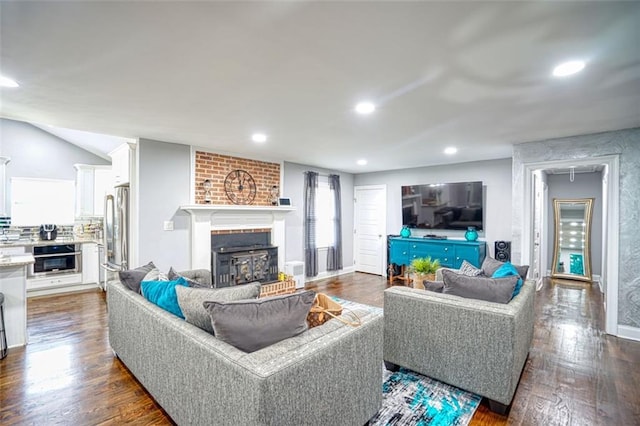 living room featuring a brick fireplace, vaulted ceiling, and dark hardwood / wood-style floors