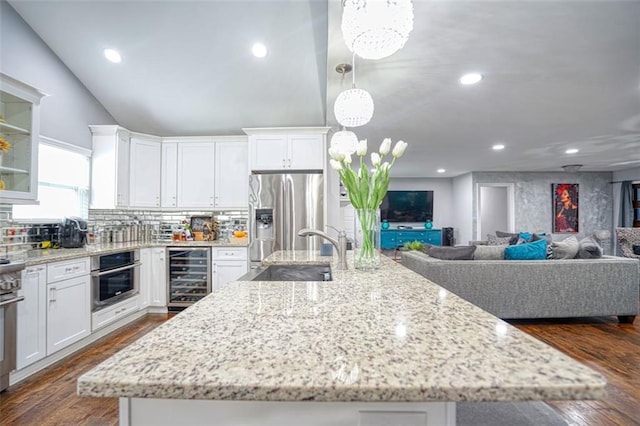 kitchen featuring a sink, a spacious island, white cabinets, appliances with stainless steel finishes, and wine cooler