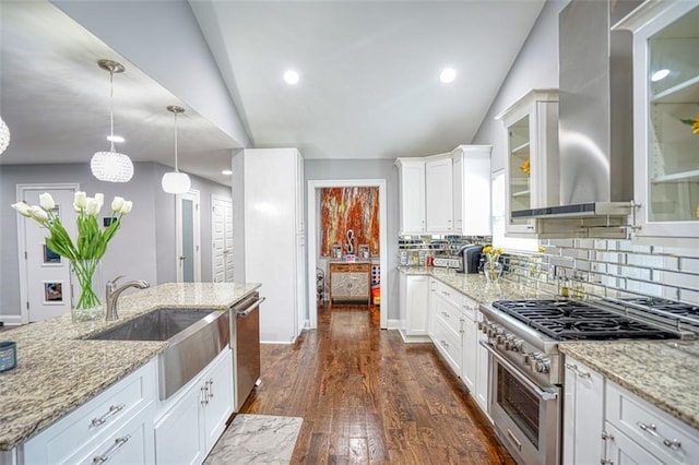 kitchen featuring vaulted ceiling, wall chimney range hood, stainless steel appliances, and a sink