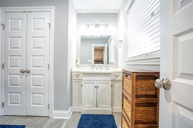 bathroom with baseboards, vanity, and a closet