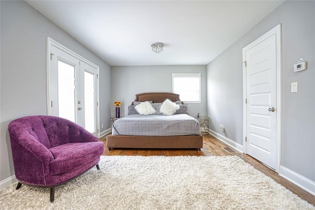 bedroom featuring baseboards, french doors, and wood finished floors