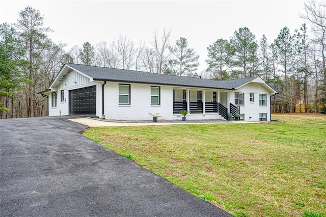 single story home with a front lawn, a porch, a garage, brick siding, and aphalt driveway