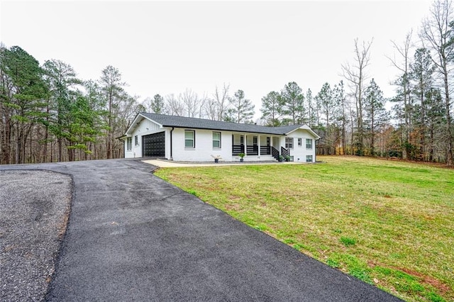 single story home with a front lawn, covered porch, a garage, brick siding, and aphalt driveway