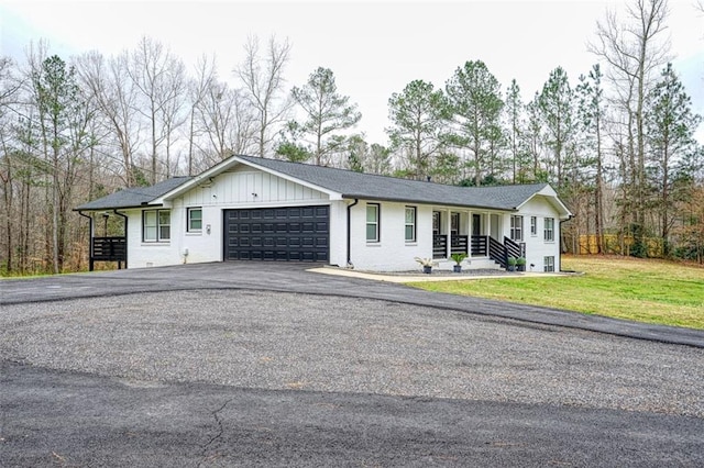 view of front of home with aphalt driveway, a front yard, board and batten siding, and a garage