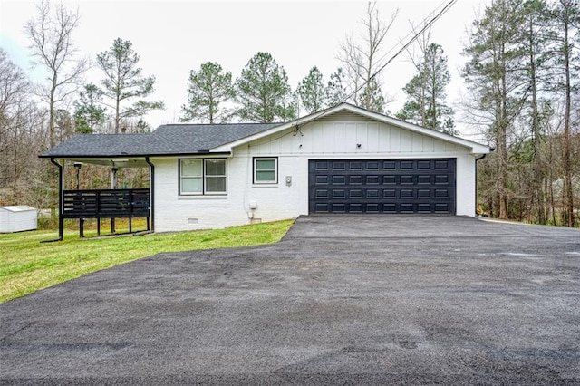 ranch-style home featuring crawl space, a garage, aphalt driveway, board and batten siding, and a front yard