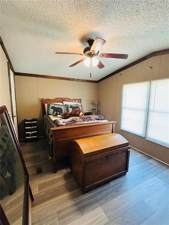 bedroom featuring ornamental molding, lofted ceiling, a textured ceiling, and wood finished floors