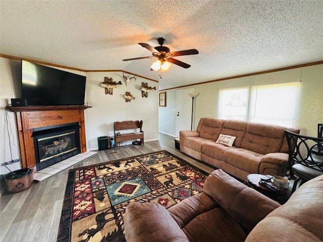 living area featuring ornamental molding, a textured ceiling, a fireplace with flush hearth, and wood finished floors