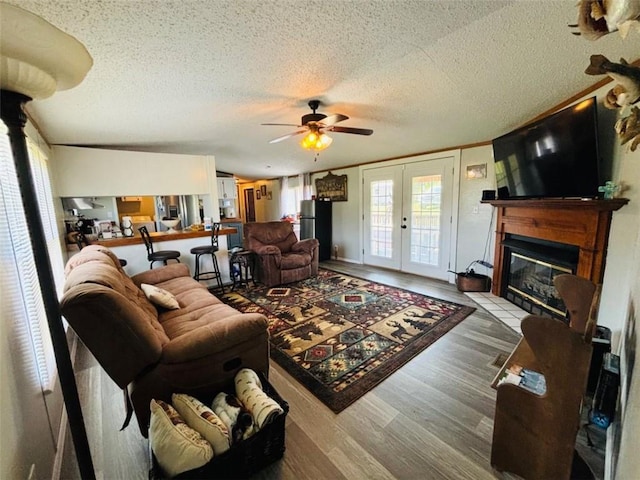 living room featuring a fireplace with flush hearth, french doors, a textured ceiling, and wood finished floors