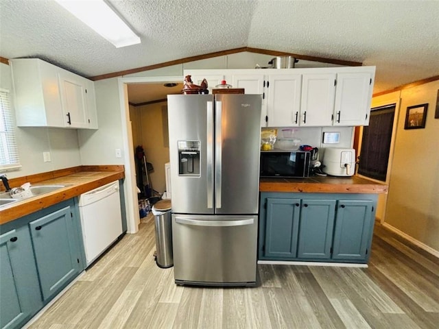 kitchen with stainless steel fridge, white dishwasher, vaulted ceiling, black microwave, and wooden counters