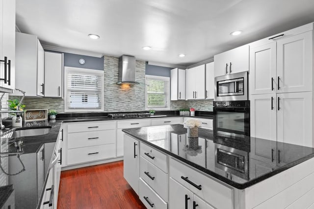 1647 Grandeus Ln SW, Stone Mountain, GA 30087 - kitchen featuring wall chimney exhaust hood, black appliances, a kitchen island, tasteful backsplash, and dark wood finished floors