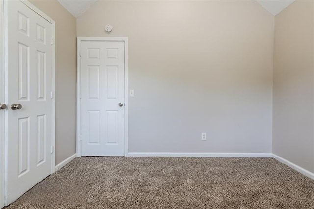 carpeted empty room with lofted ceiling and baseboards