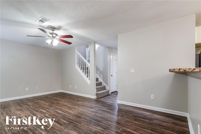 unfurnished living room featuring ceiling fan, dark hardwood / wood-style floors, and a textured ceiling