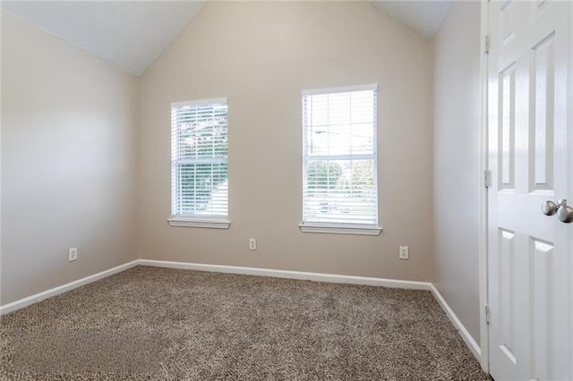 carpeted spare room with vaulted ceiling and baseboards