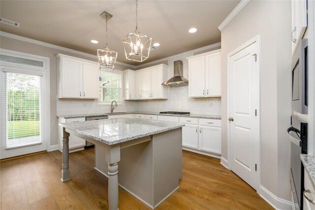 8245 Dawson View Way, Cumming, GA 30028 - kitchen with wall chimney exhaust hood, crown molding, a kitchen island, a chandelier, and white cabinetry