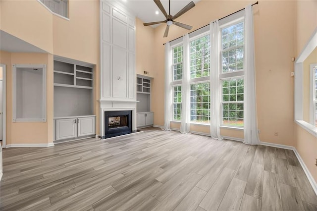 5156 Amberden Hall Dr, Suwanee, GA 30024 - unfurnished living room featuring a high ceiling, ceiling fan, light wood-style floors, a large fireplace, and baseboards