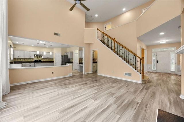 5156 Amberden Hall Dr, Suwanee, GA 30024 - unfurnished living room with stairs, a ceiling fan, light wood-style floors, a high ceiling, and baseboards
