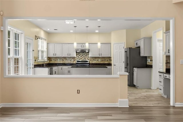 5156 Amberden Hall Dr, Suwanee, GA 30024 - kitchen with dark countertops, under cabinet range hood, light wood-style floors, decorative backsplash, and recessed lighting