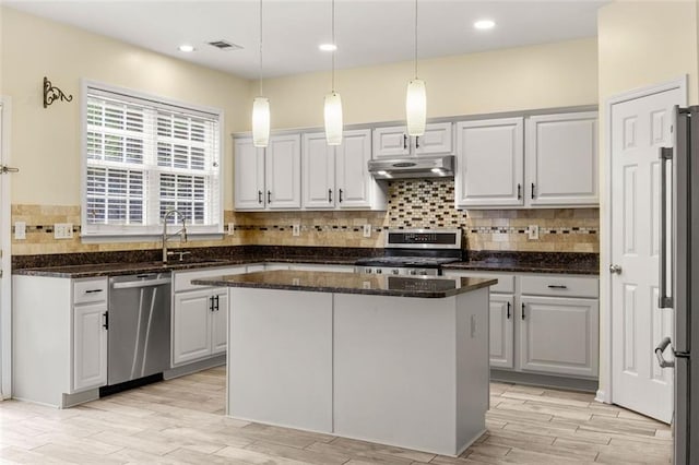 5156 Amberden Hall Dr, Suwanee, GA 30024 - kitchen with appliances with stainless steel finishes, under cabinet range hood, decorative backsplash, dark stone counters, and light wood-style floors