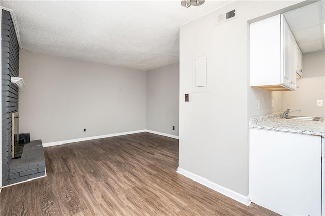 6354 Shannon Pkwy Unit 30C, Union City, GA 30291 - unfurnished living room featuring wood finished floors, a sink, a fireplace, baseboards, and a textured ceiling
