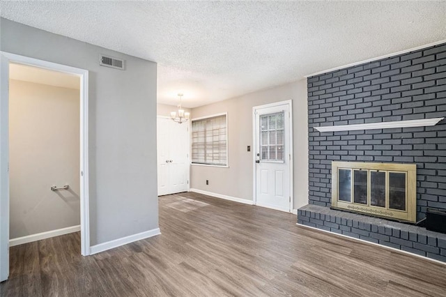6354 Shannon Pkwy Unit 30C, Union City, GA 30291 - unfurnished living room featuring wood finished floors, a brick fireplace, a chandelier, baseboards, and a textured ceiling