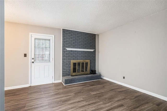 6354 Shannon Pkwy Unit 30C, Union City, GA 30291 - unfurnished living room with wood finished floors, a textured ceiling, a brick fireplace, and baseboards