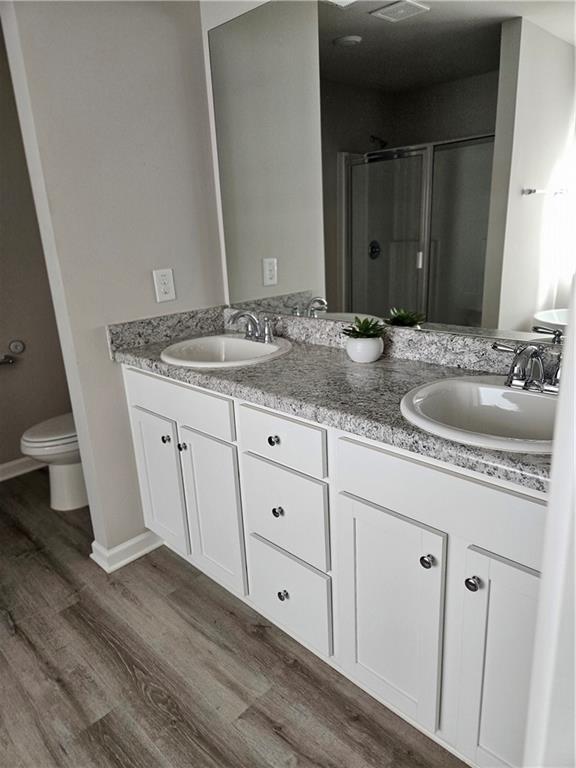 bathroom with a tub to relax in, vanity, wood-type flooring, and toilet