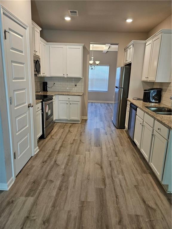 kitchen featuring white cabinets, tasteful backsplash, appliances with stainless steel finishes, light wood-type flooring, and sink