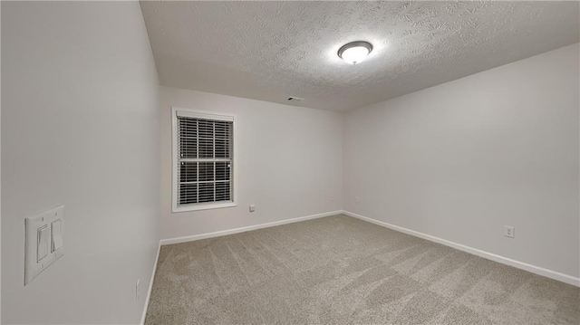 empty room with carpet floors and a textured ceiling