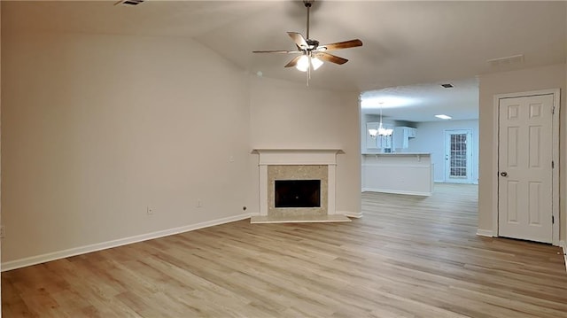 unfurnished living room featuring lofted ceiling, ceiling fan with notable chandelier, and light wood-type flooring