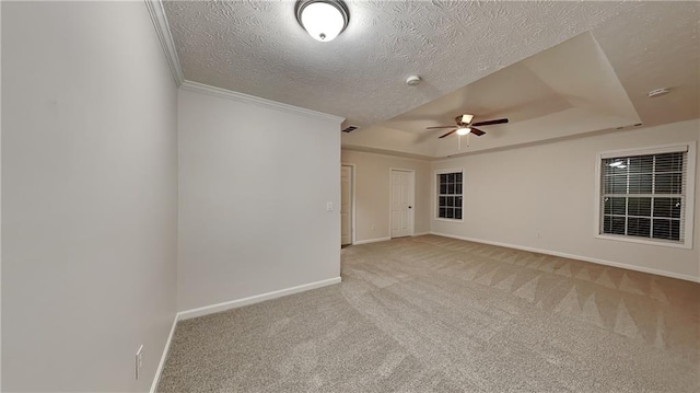 carpeted spare room with ceiling fan, ornamental molding, a tray ceiling, and a textured ceiling