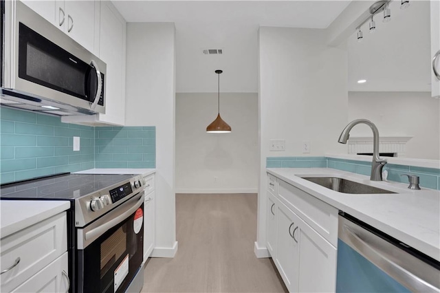 kitchen with hanging light fixtures, sink, white cabinets, and stainless steel appliances