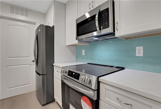 kitchen featuring decorative backsplash, white cabinetry, and appliances with stainless steel finishes