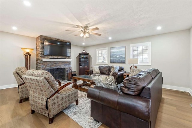 living room with a fireplace, ceiling fan, and light wood-type flooring