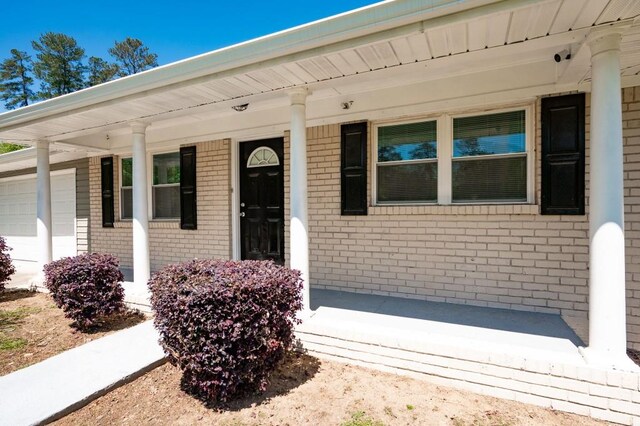 4284 Carlos Ct, Powder Springs, GA 30127 - property entrance with an attached garage, a porch, and brick siding