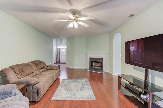 965 Under Ct, Sugar Hill, GA 30518 - living room featuring a ceiling fan, wood finished floors, a fireplace with raised hearth, arched walkways, and baseboards