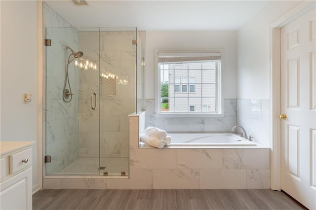 full bath with a stall shower, a bath, and wood finished floors